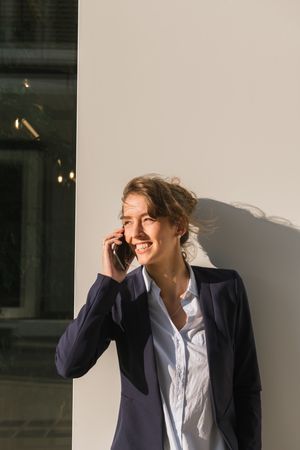 Cheerful female manager speaking on smartphone on street