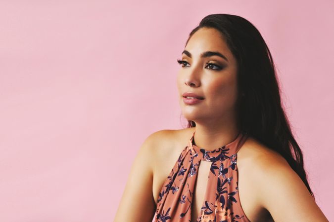 Hispanic woman looking away in pink room