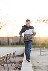 Teenager wearing a red hat walking in city park