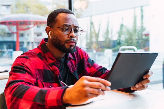 Black male surfing tablet in cafe