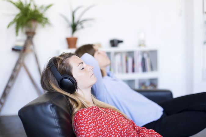 Two women relaxing in living room with eyes closed