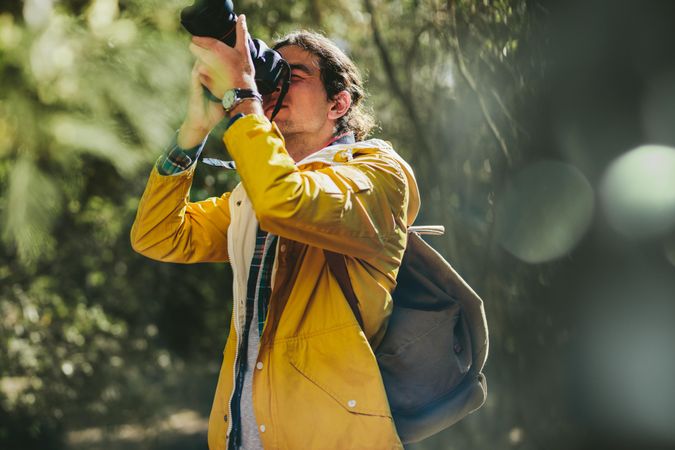 Photographer wearing jacket and backpack taking nature photography