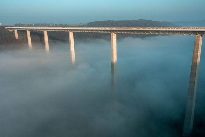 Autobahn bridge over dense fog, drone aerial view, at sunrise in Germany