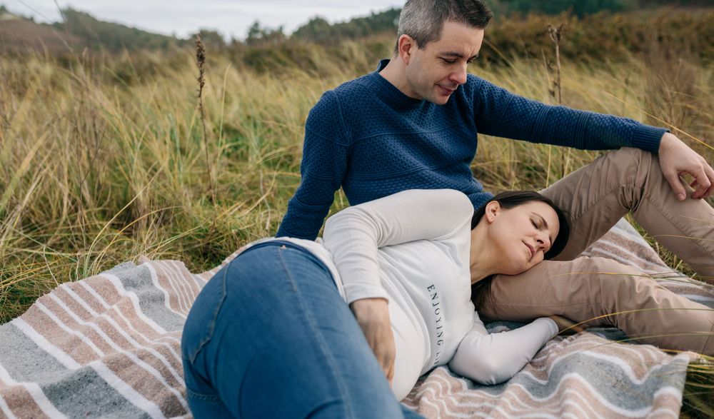 Man looking pregnant woman resting on the grass