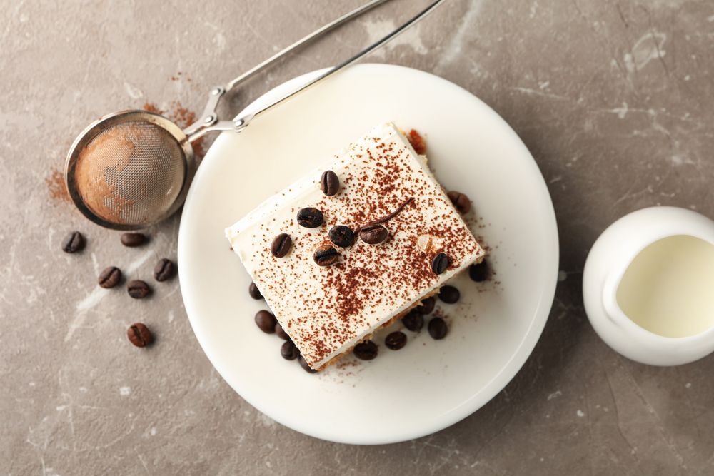 Composition with plate of tiramisu on light brown background. Tasty dessert