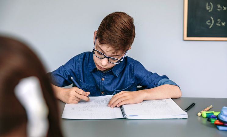 Teenager writing in notebook at school