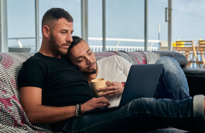 Happy gay couple using laptop at home