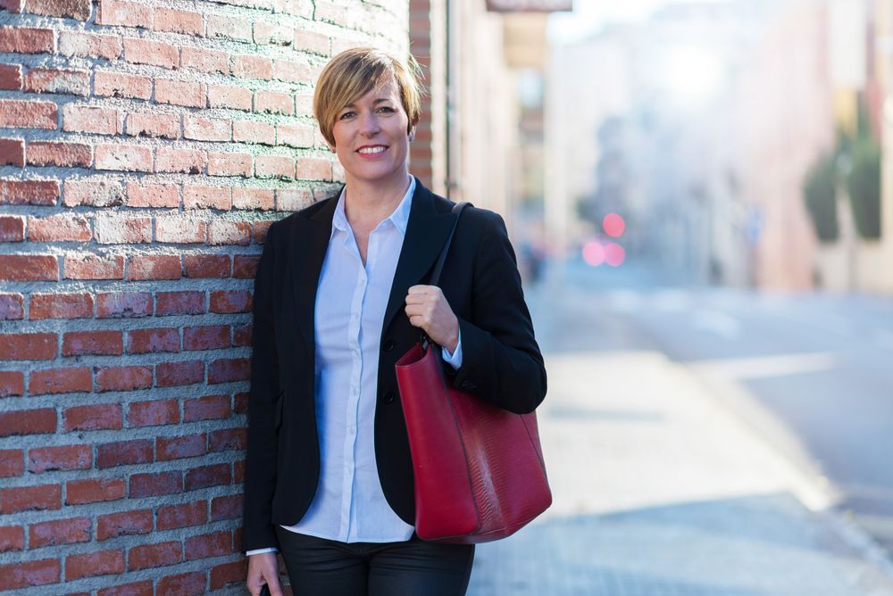 Confident businesswoman standing in front of brickwall outside