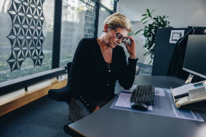 Mature businesswoman looking tired sitting at her desk