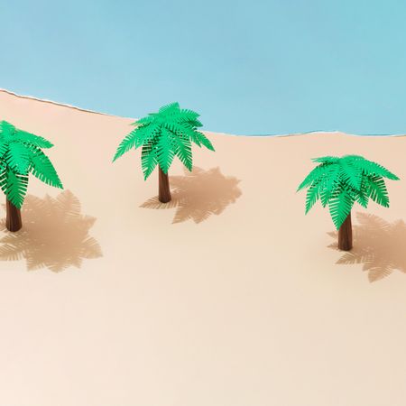 Tropical palm trees on sandy beach made of paper