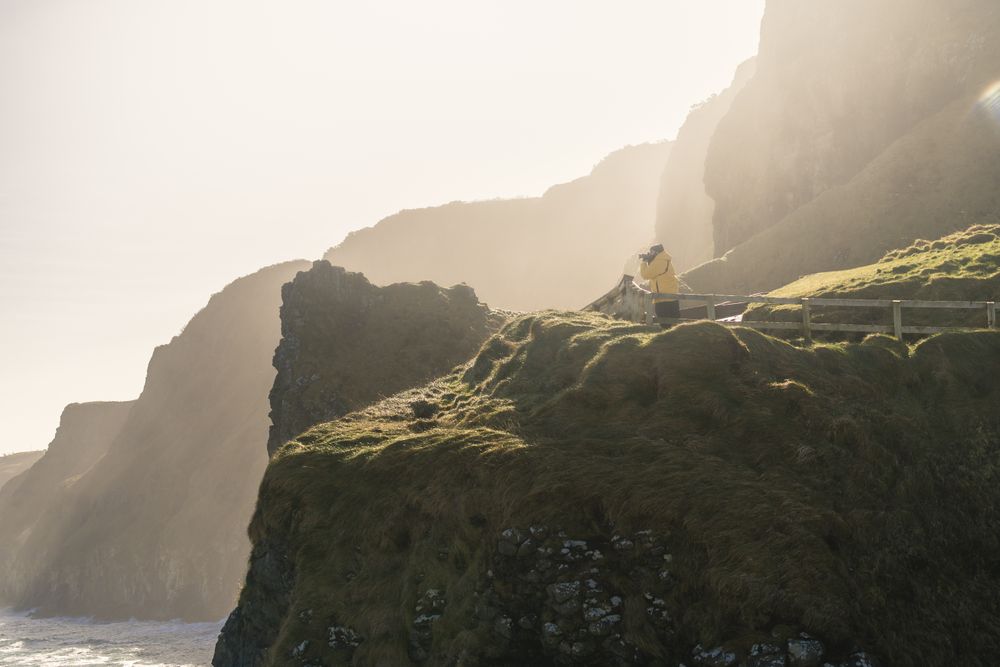 Man standing on country road and taking picture of sea with camera