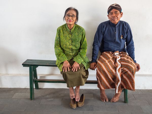Java Island, Indonesia - August, 14 2015: Barefoot people on bench in palace yard