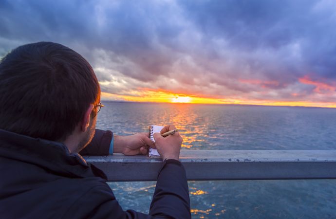 Man writing in a notebook at sunset