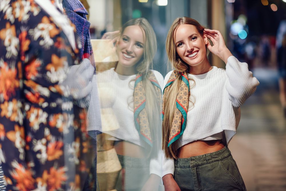 Smiling woman leaning on shop window at night