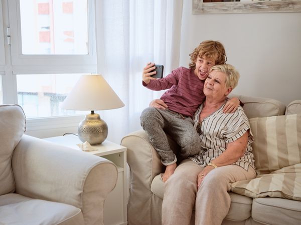 Cheerful boy taking selfie on couch