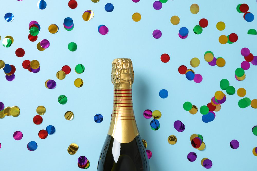 Champagne bottle and glitter on blue background, space for text