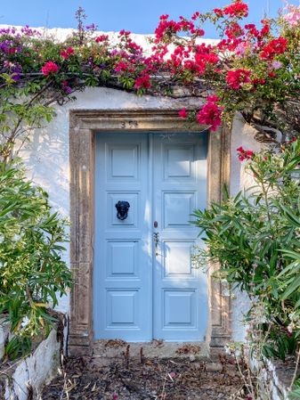 Patmian door with figure head and overgrown Bougainvillea