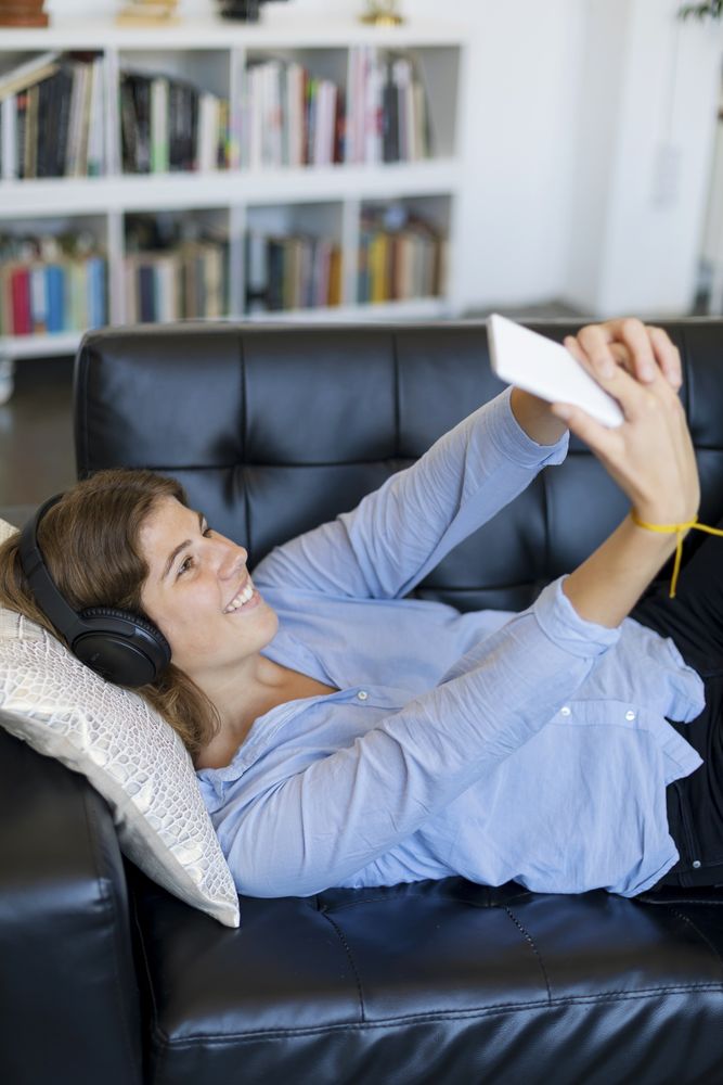 Woman lying on a sofa taking selfie on her phone
