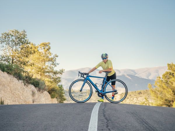 man resting while riding a bicycle on a mountain road