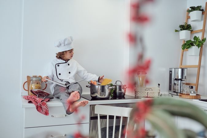 Adorable preteen boy in chef suit reading culinary book