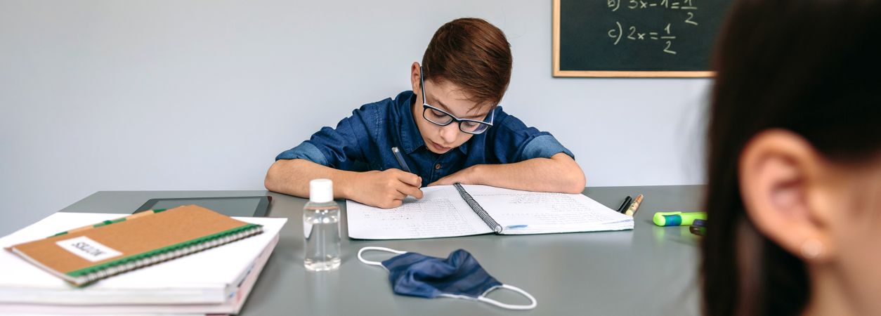 Boy writing in his notebook at school