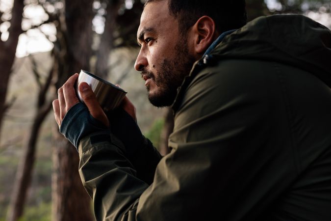 Portrait of male hiker taking rest outdoors holding coffee
