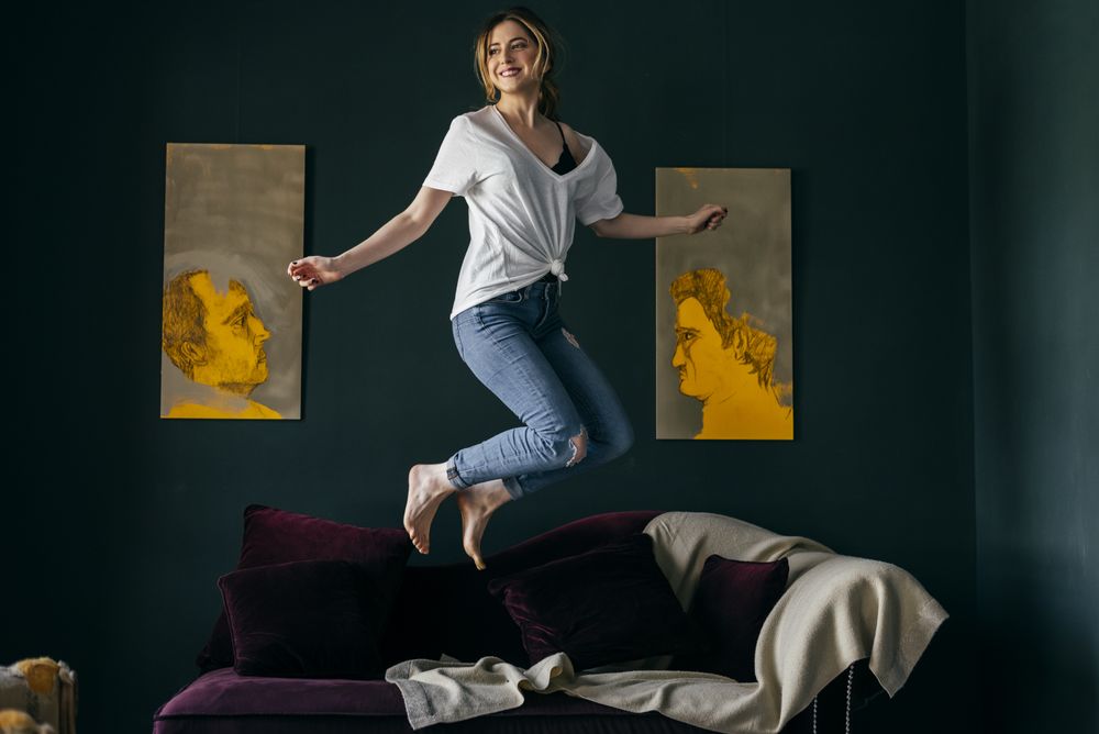 Young woman jumping on couch in stylish room