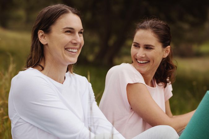 Close up of two smiling women sitting in park