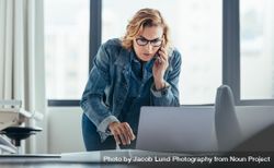 Female CEO working at computer and talking on mobile phone 4m9gv4