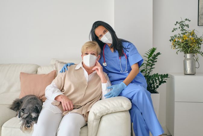 Physician embracing patient on sofa with dog after examination