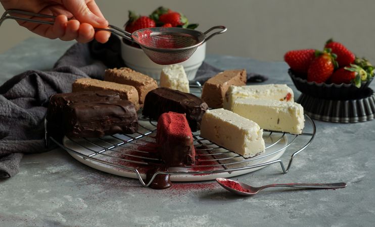 Person near chocolate and strawberry cakes