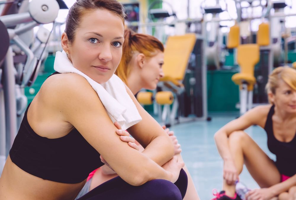 Portrait of serious woman sitting in group at gym