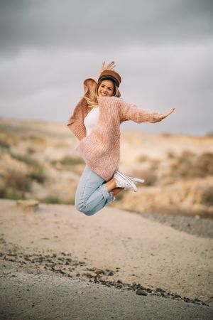 Cheerful woman jumping in desert landscape