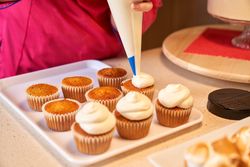 Crop confectioner icing cupcakes with buttercream