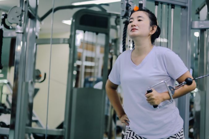 A woman is using a cable machine at a gym.