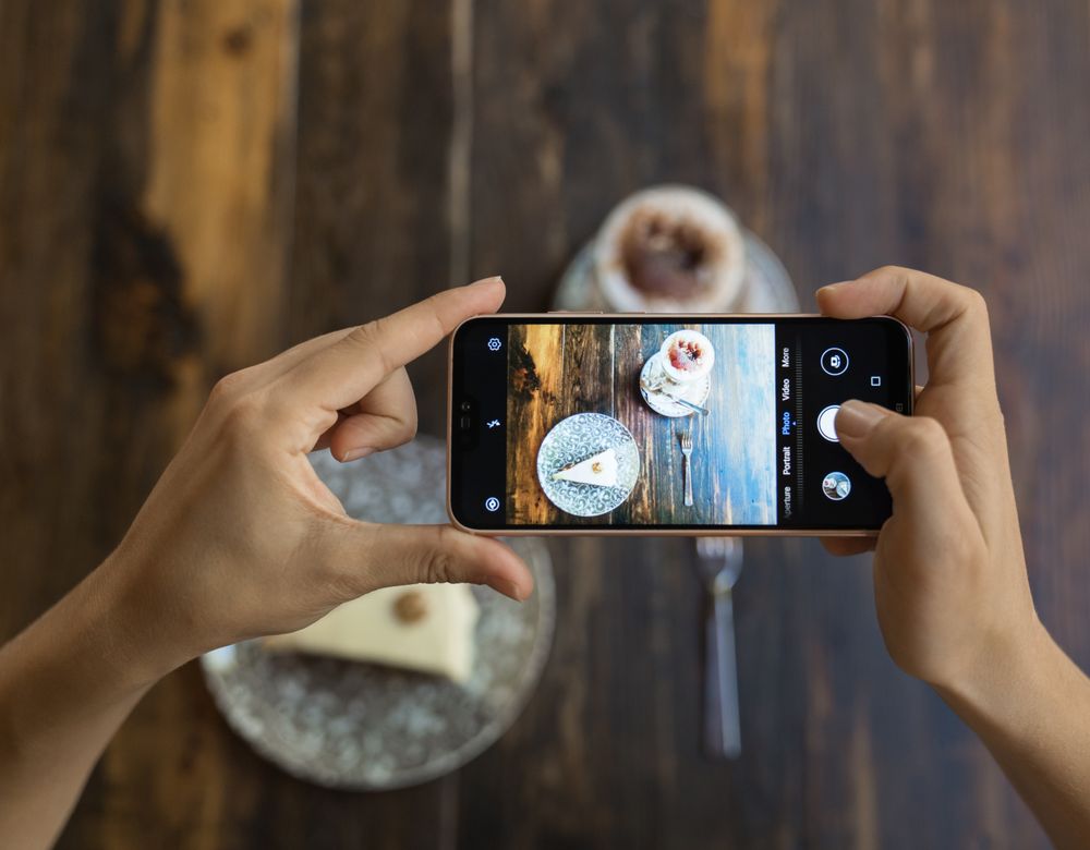 Faceless person taking picture of cake and coffee