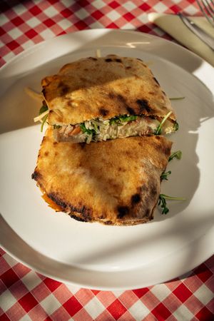 Grilled flatbread sandwich with greens on plate at restaurant