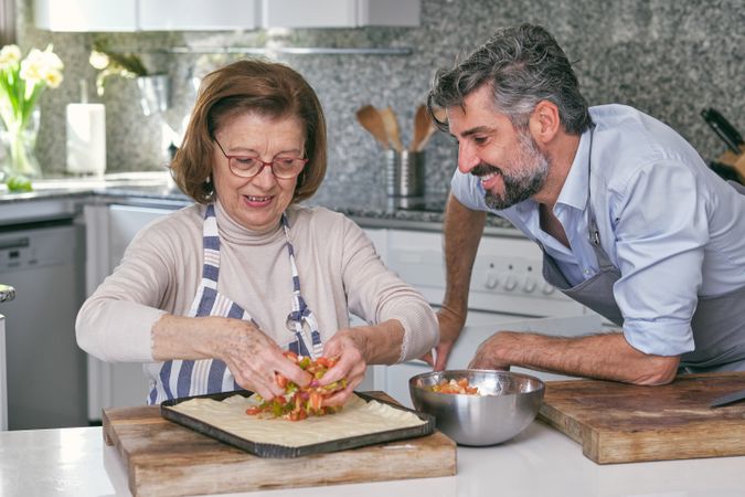 Son and mother cooking pie in kitchen