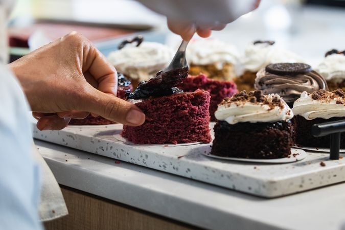 Crop cook smearing jam on cakes in kitchen