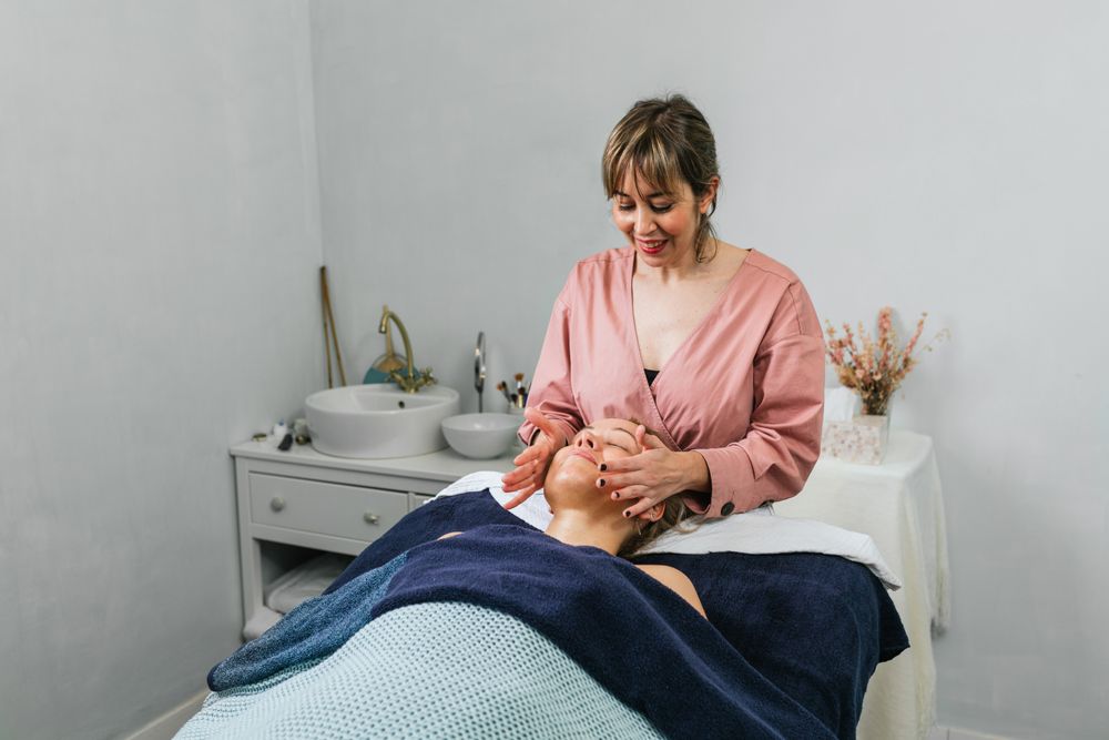 Smiling masseuse doing massage for woman in spa salon