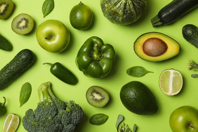 Vegetables and fruits on green background, top view