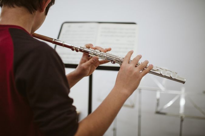Focused student playing music using his flute instrument