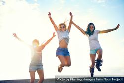 Happy female friends jumping for joy on sunny day 5QpZ90