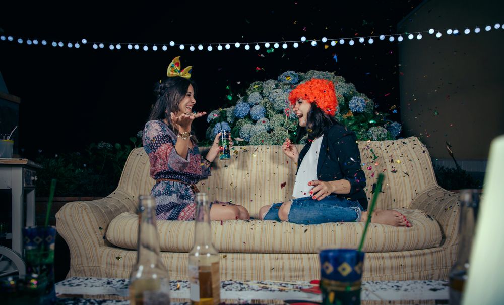 Happy women having fun sitting on sofa in party with confetti