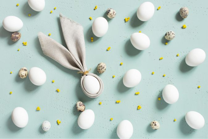 Bunny ear shaped napkin on blue background with quail egg patterns