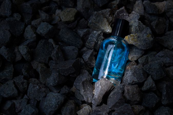 Light blue perfume bottle mock up laying in rocky terrain