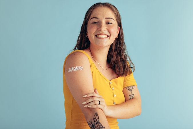 Portrait of a young woman showing her arm after receiving vaccine dose