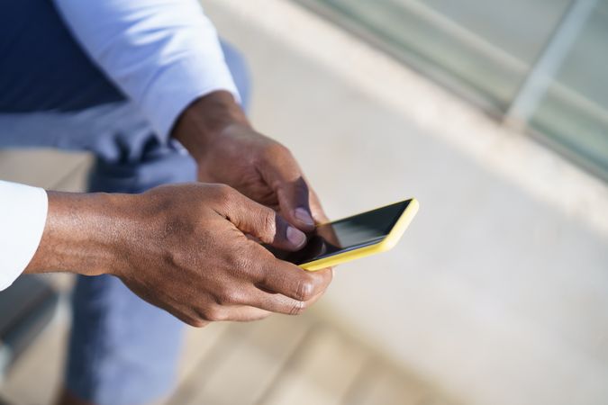 Close up of hands of Black man holding a yellow phone