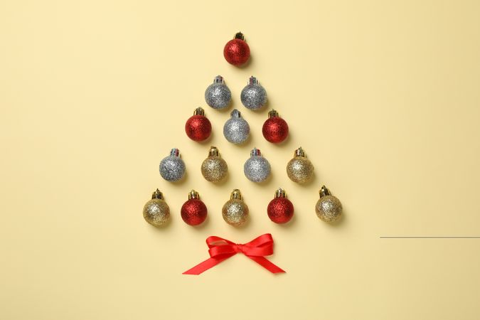 Christmas tree made of baubles on beige background, space for text
