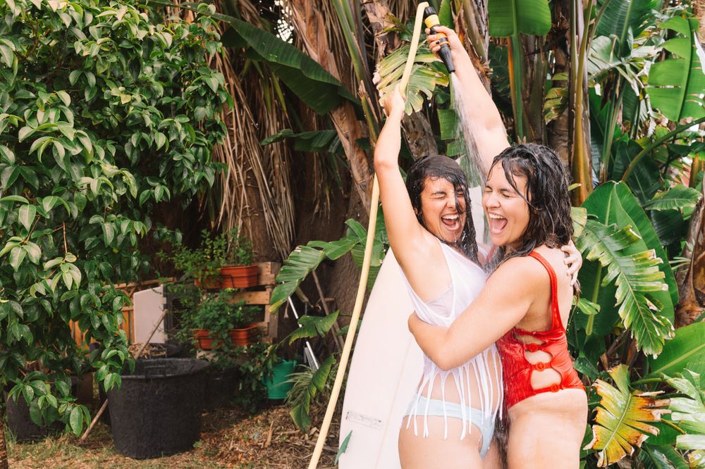 Girlfriends showering with hose in garden